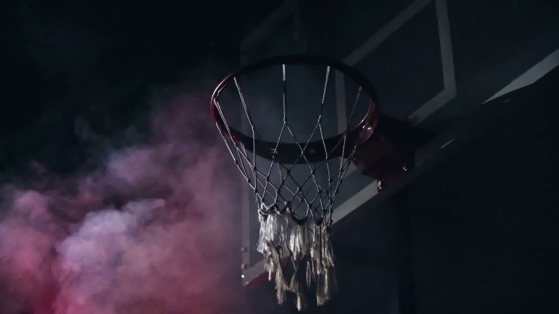 low-angle-view-of-man-throwing-ball-into-basketball-hoop-in-slow-motion-in-the-darkness-with-red-smoke-in-the-background_h9lddux3s_thumbnail-full01